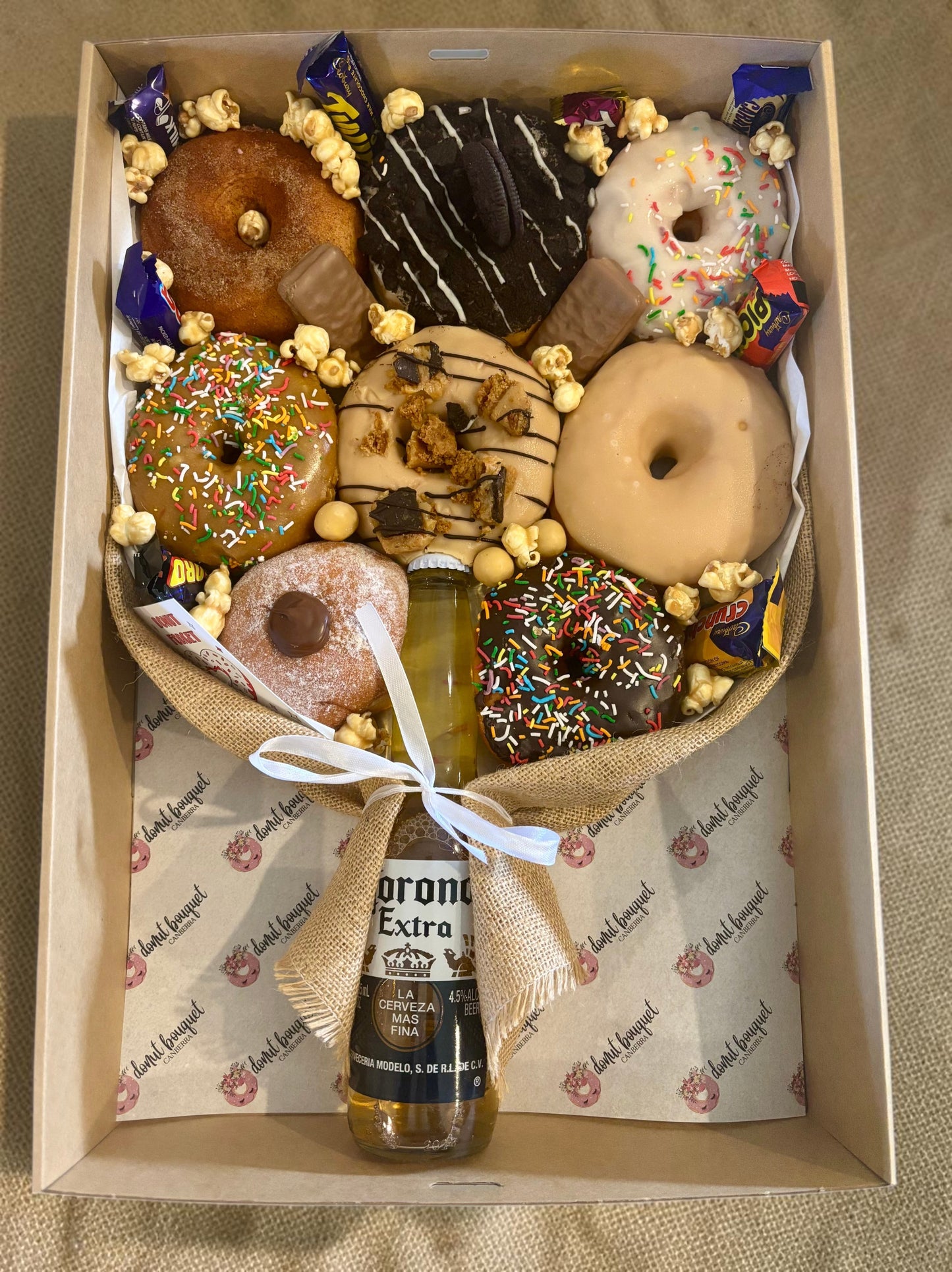 Donut Bouquet Canberra gift box featuring assorted glazed donuts, chocolate bars, popcorn, and a Corona beer bottle.