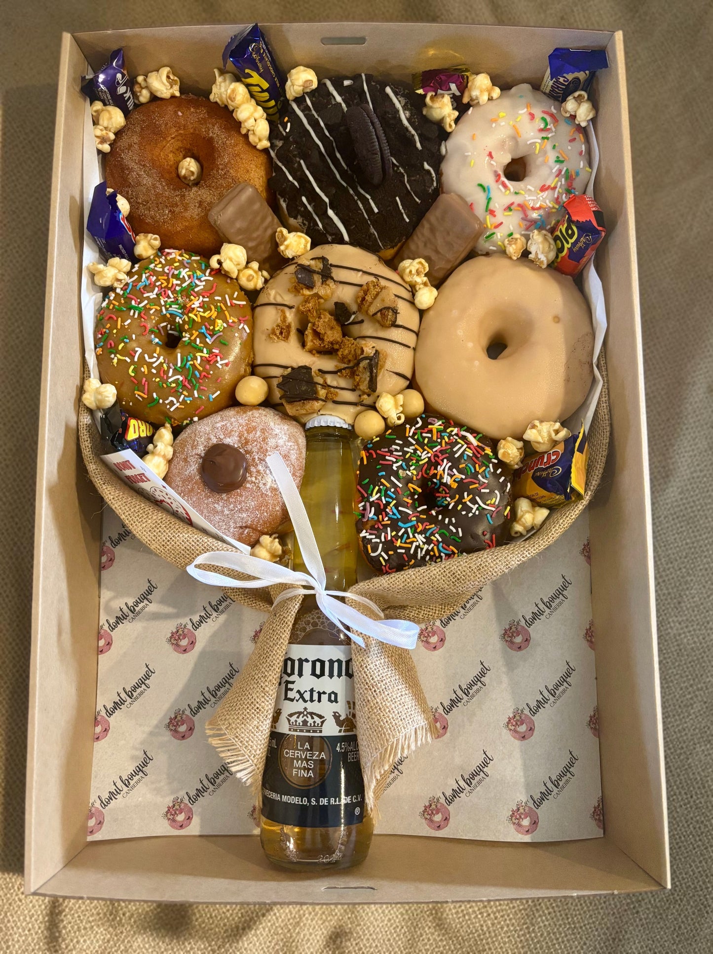Donut Bouquet Canberra gift box featuring assorted glazed donuts, chocolate bars, popcorn, and a Corona beer bottle.
