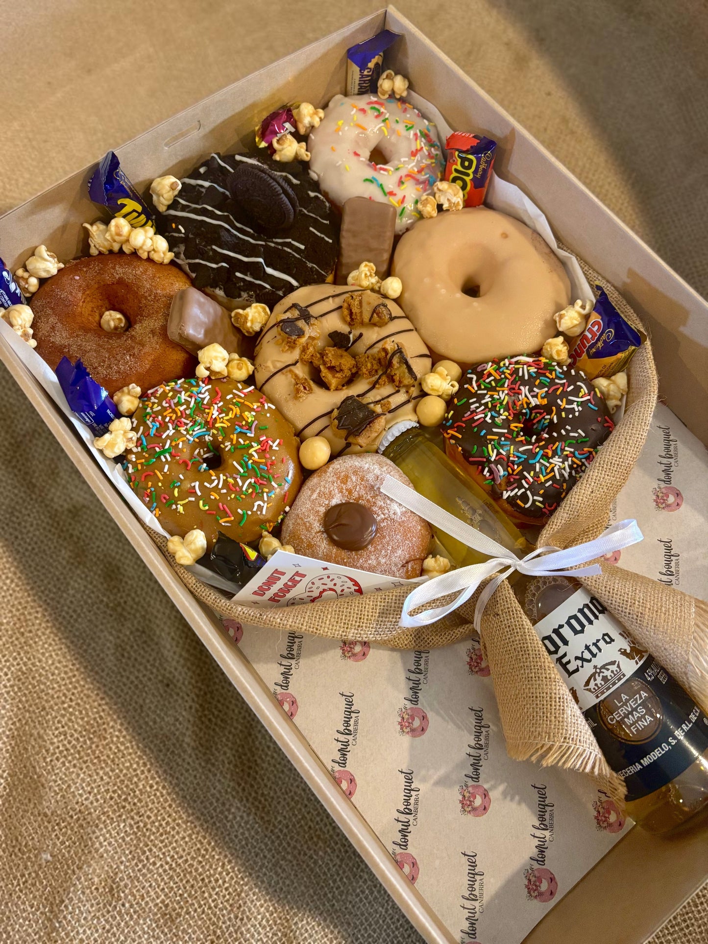 Donut Bouquet Canberra gift box featuring assorted glazed donuts, chocolate bars, popcorn, and a Corona beer bottle.