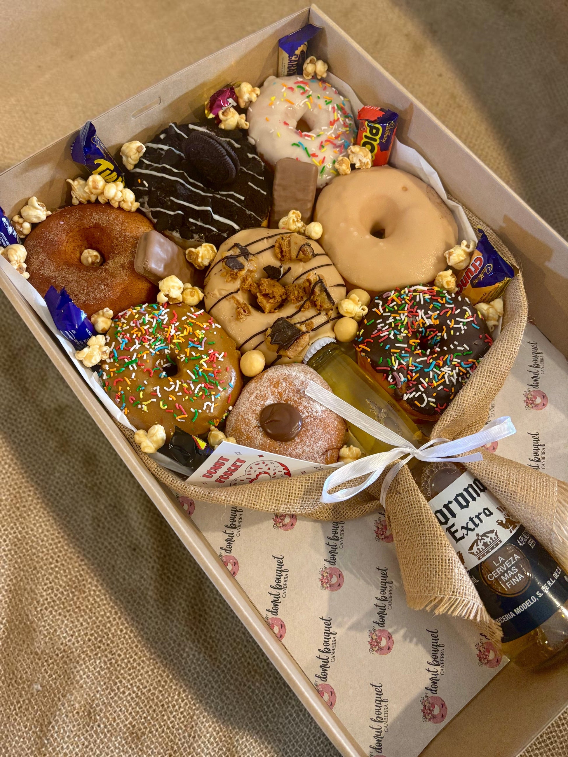 Donut Bouquet Canberra gift box featuring assorted glazed donuts, chocolate bars, popcorn, and a Corona beer bottle.