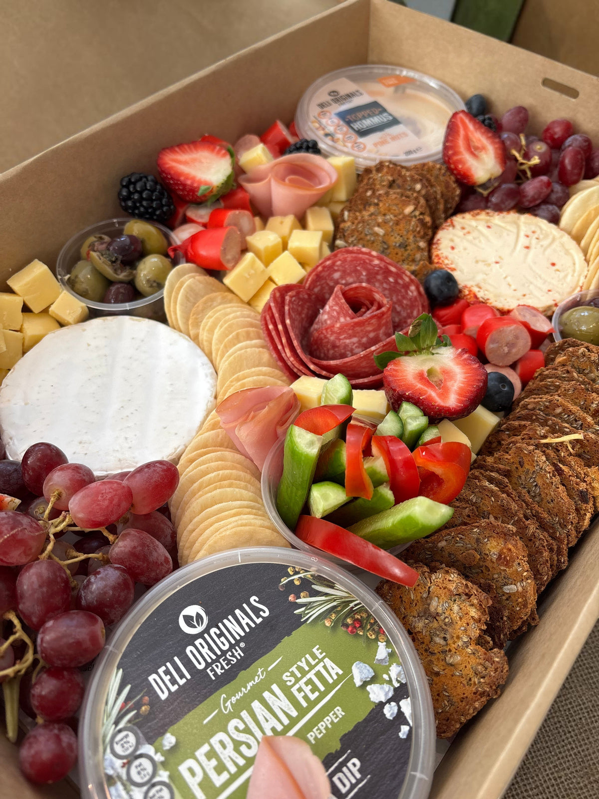 Donut Bouquet Canberra grazing box featuring assorted cheeses, sliced meats, fresh strawberries, olives, and crackers.