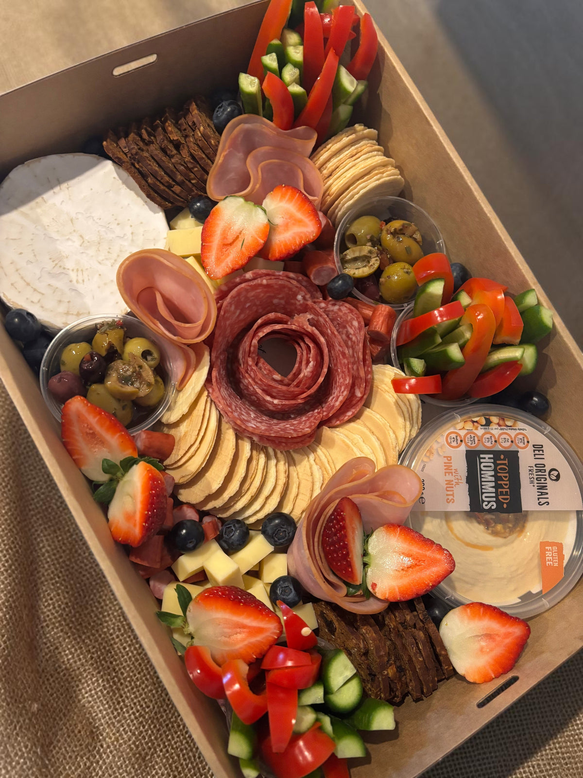 Donut Bouquet Canberra grazing box filled with assorted cheeses, sliced meats, fresh strawberries, olives, and hummus.