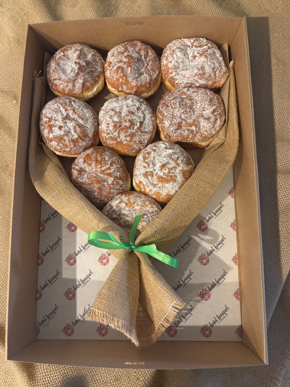 Donut Bouquet Canberra jam donut bouquet featuring nine powdered sugar donuts wrapped in hessian with a ribbon
