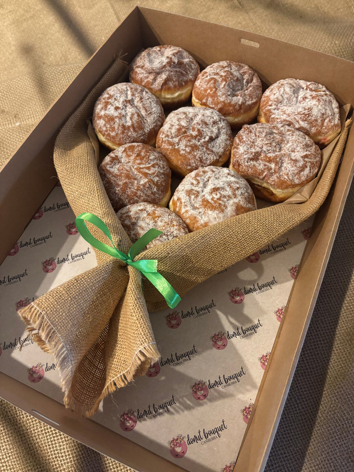 Donut Bouquet Canberra jam donut bouquet featuring nine powdered sugar donuts wrapped in hessian with a ribbon