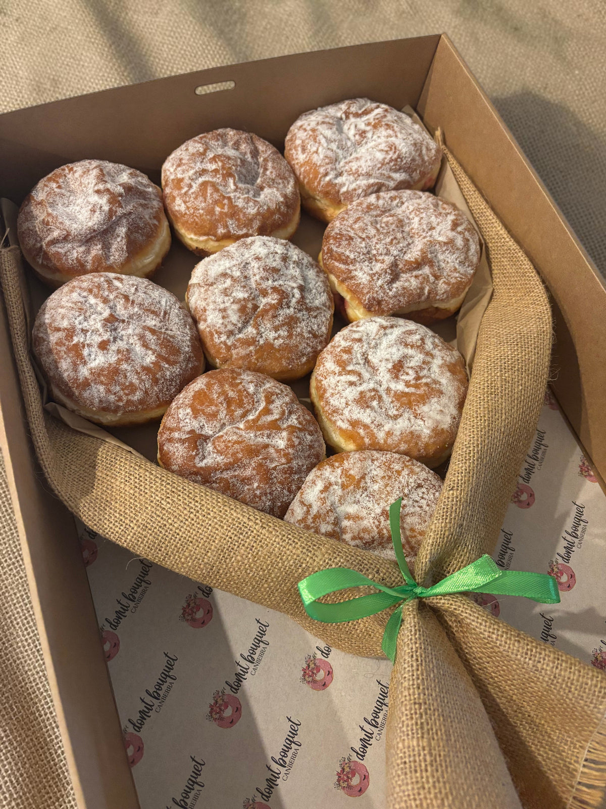 Donut Bouquet Canberra jam donut bouquet featuring nine powdered sugar donuts wrapped in hessian with a ribbon