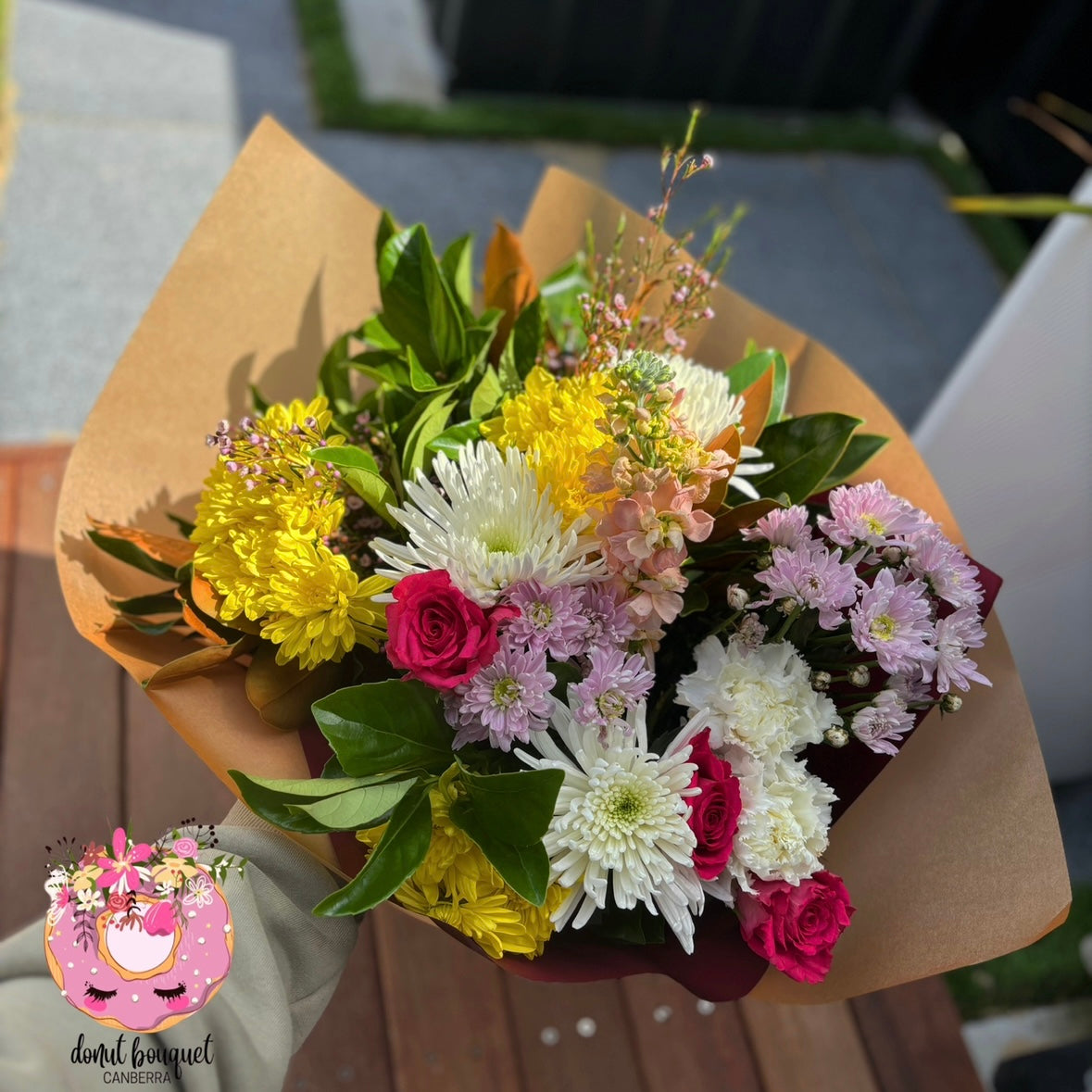 Donut Bouquet Canberra Indulgence Add-On bouquet featuring yellow, white, pink, and red flowers in brown paper wrap