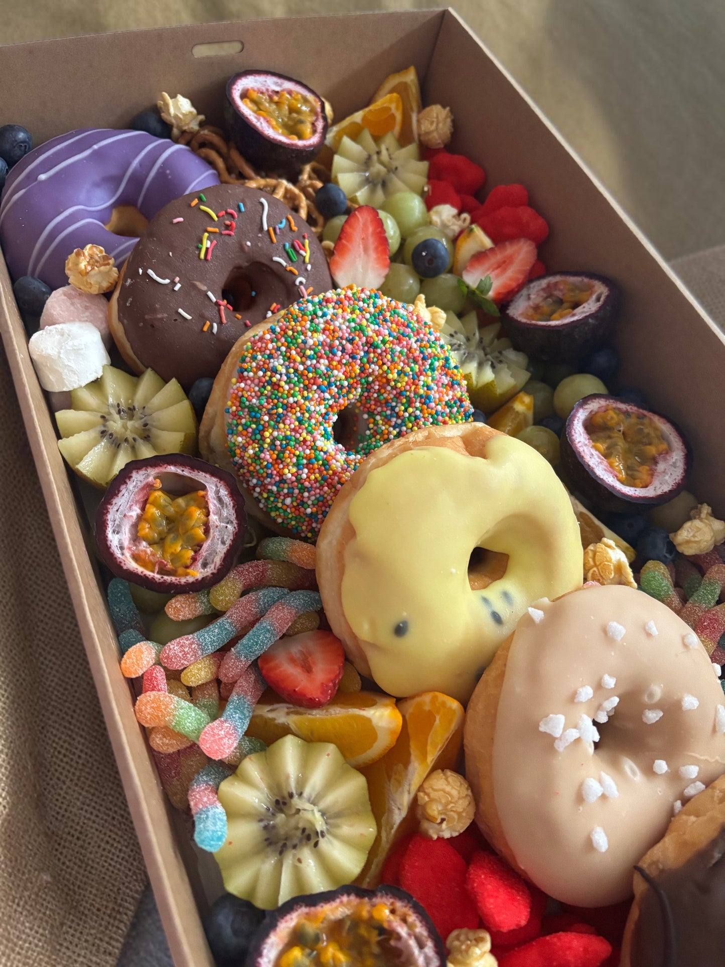 Donut Bouquet Canberra sweets grazing box filled with assorted donuts, pretzels, lollies, and chocolate treats, mixed with fruit.