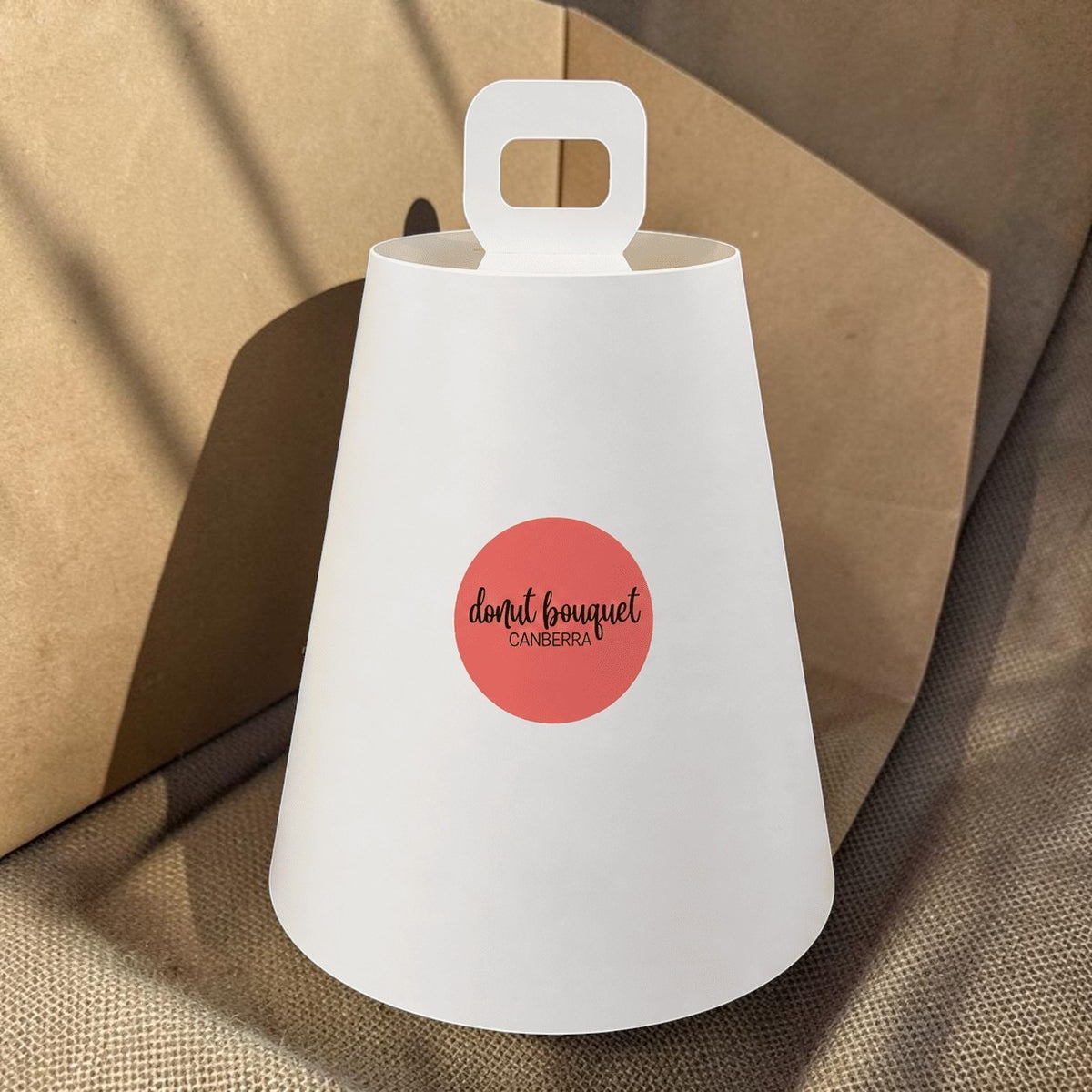 Donut Bouquet Canberra vegan high tea gift set featuring a white protective cover with a branded circular logo
