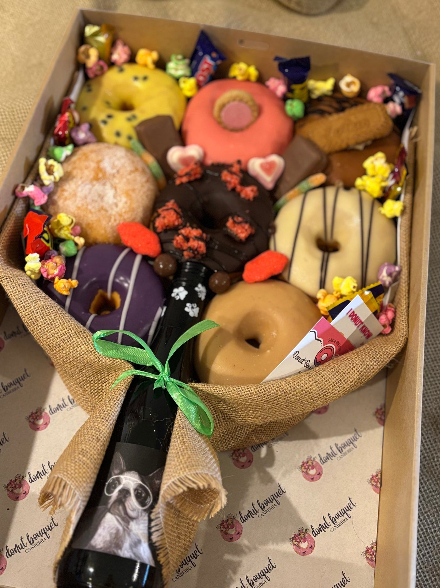 Donut Bouquet Canberra gift box featuring eight assorted donuts, chocolates, lollies, and a bottle of wine.